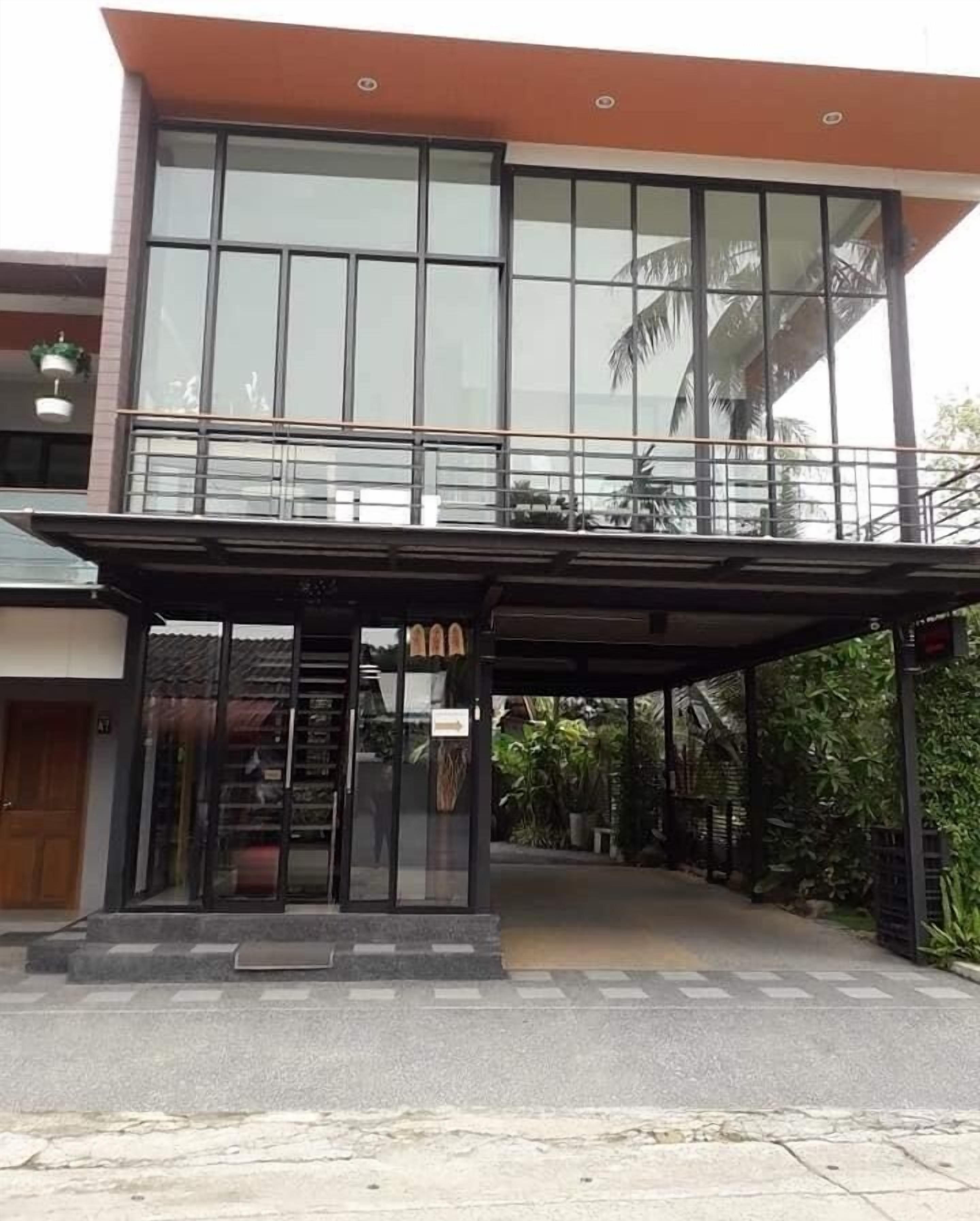 A modern building with a glass facade, a covered entrance, and a balcony.