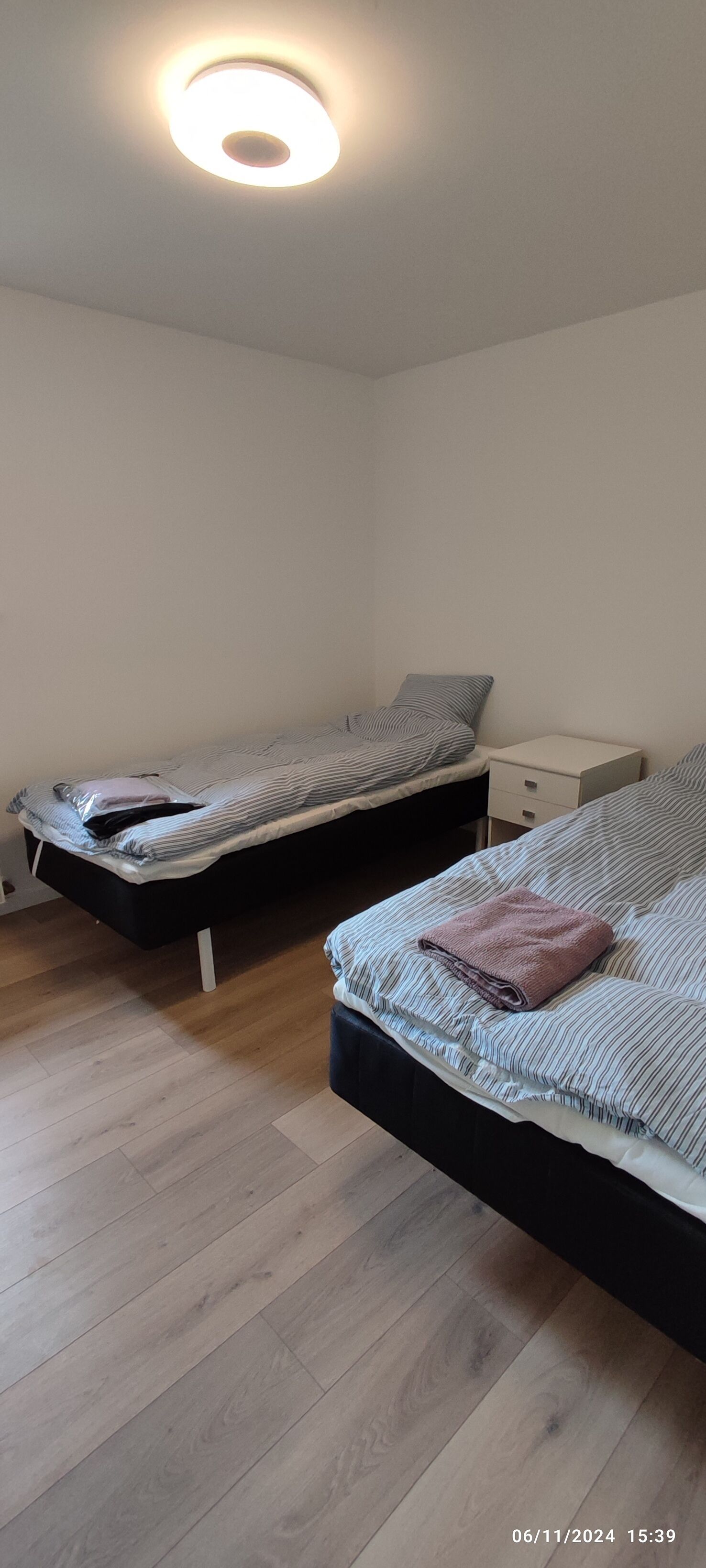 Un dormitorio con dos camas, una mesita de noche y una lámpara en el techo.