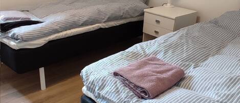 Une chambre avec deux lits, une table de chevet et une lampe.