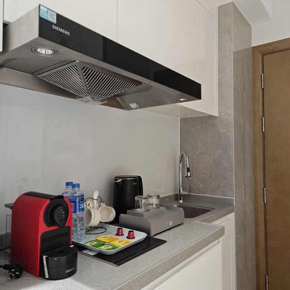 A compact kitchen with a Siemens range hood, a coffee machine, a water dispenser, and a small sink. - ZhuHai BoShengManZhiHuiFuWuGongYu (Zhuhai)