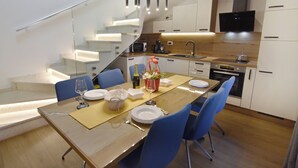 Une cuisine moderne avec un coin repas, un escalier et un téléviseur fixé au-dessus de la cuisinière.