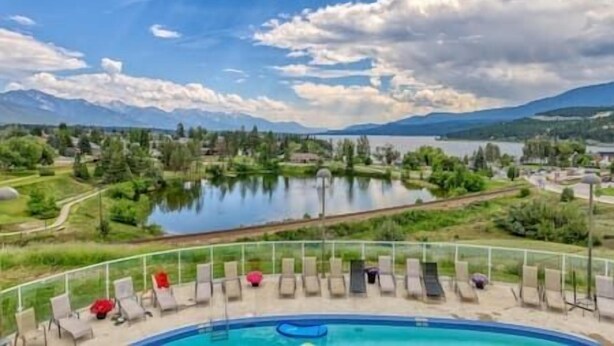A pool area with lounge chairs and a view of a lake and mountains. - Top Floor / Heron Point / Hot tub / Pool / AC (Invermere)
