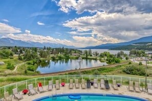 A pool area with lounge chairs and a view of a lake and mountains. - Top Floor / Heron Point / Hot tub / Pool / AC (Invermere)
