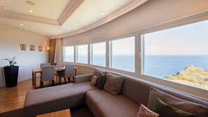 A modern living room with a curved ceiling, a large sofa, a dining area, and a view of the sea. - HOTEL NEUSCHLOSS OTARU (Otaru)