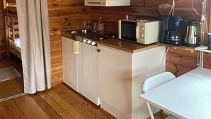 A compact kitchen with wooden walls, a microwave, a kettle, and a coffee maker.