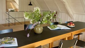 A dining area with a wooden table, black chairs, a vase with flowers, and a plate of apples. - 5 Bedroom Agritourism property in Stockach (Stockach)