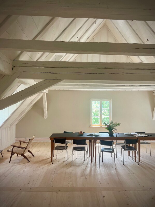 A spacious room with a high ceiling and exposed beams, a large window, and a dining table set with chairs. - 5 Bedroom Agritourism property in Stockach (Stockach)
