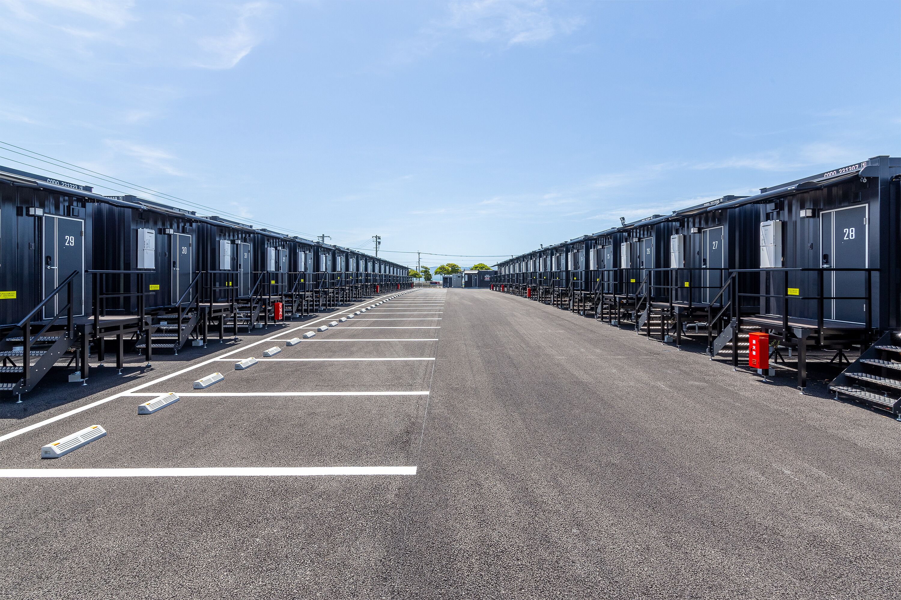 A row of black train carriages with white numbers on the doors, arranged in a straight line on a paved surface.