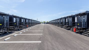 A row of black train carriages with white numbers on the doors, arranged in a straight line on a paved surface.