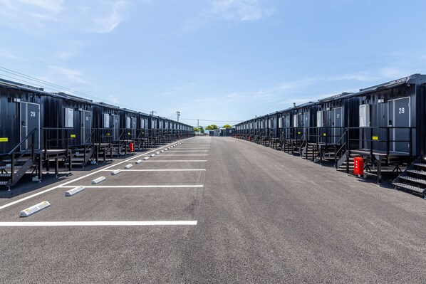 A row of black train carriages with white numbers on the doors, arranged in a straight line on a paved surface.