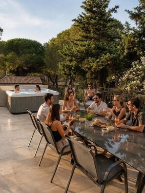 A group of people around a glass table in an outdoor setting with a hot tub and trees in the background. - Domaine La Yole Wine Resort (Vendres)