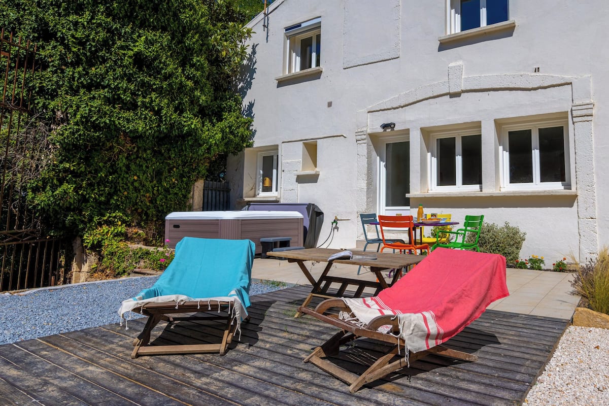 Une terrasse avec deux chaises longues, un jacuzzi et une table avec des chaises.
