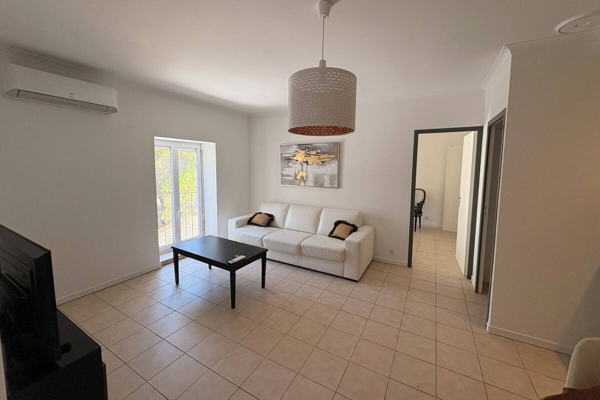Un salon moderne avec un canapé blanc, une table basse noire et un luminaire suspendu.