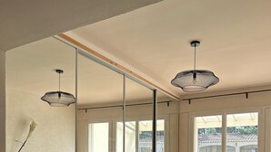 Ein Essbereich mit einem langen Holztisch, Stühlen, großen Fenstern und hängenden Pendelleuchten.