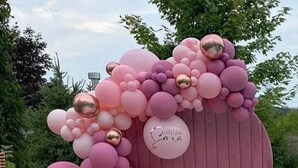 Un arco de globos rosa y dorado con un letrero que dice '¡Feliz Cumpleaños Sara!'.