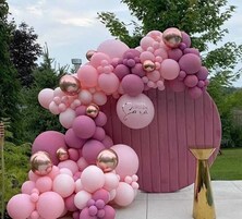 Un arco de globos rosa y dorado con un letrero que dice '¡Feliz Cumpleaños Sara!'.