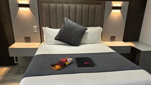 Una habitación de hotel moderna con una cama grande, dos mesitas de noche e iluminación integrada en la pared.