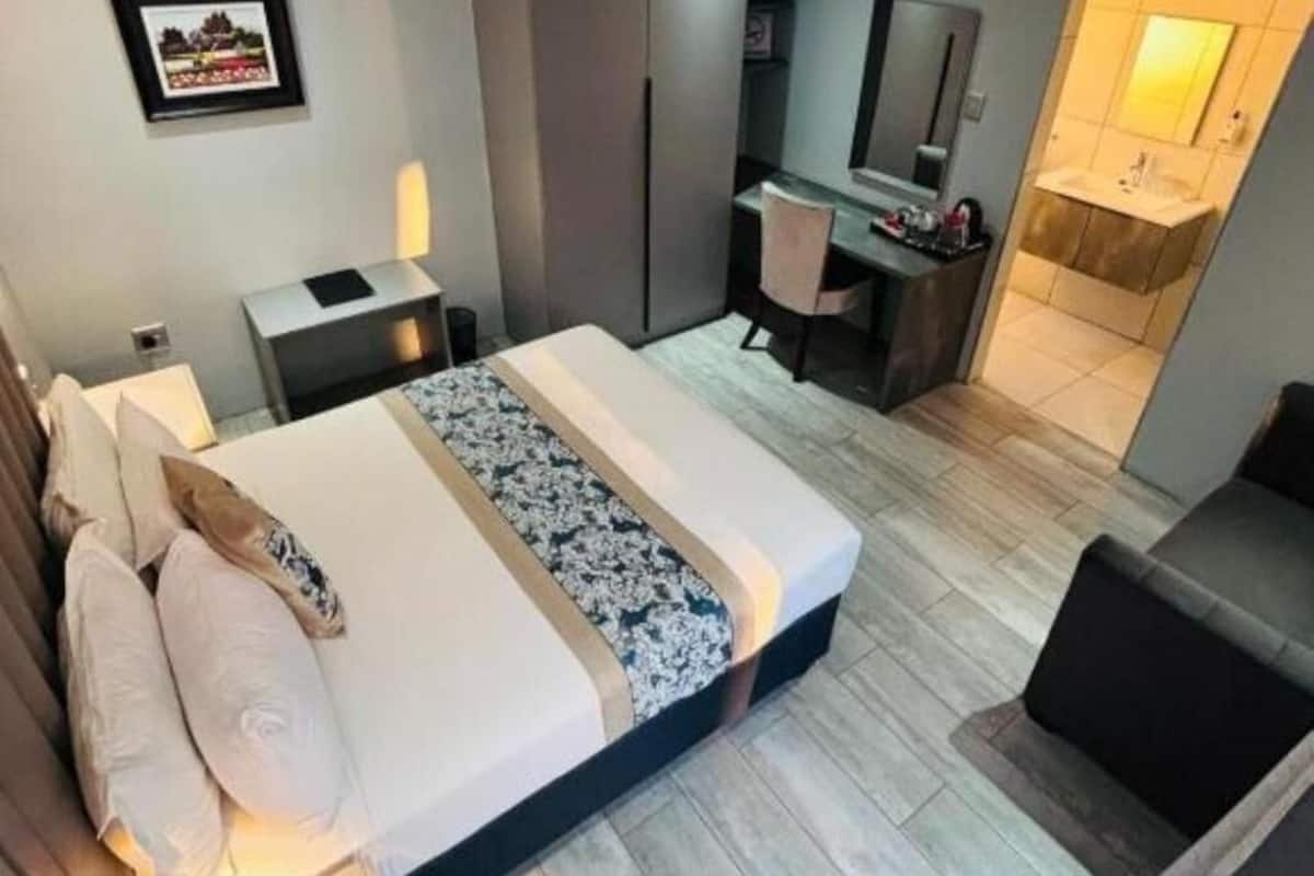 Una habitación de hotel moderna con cama, mesita de noche, escritorio y una pequeña zona de estar.