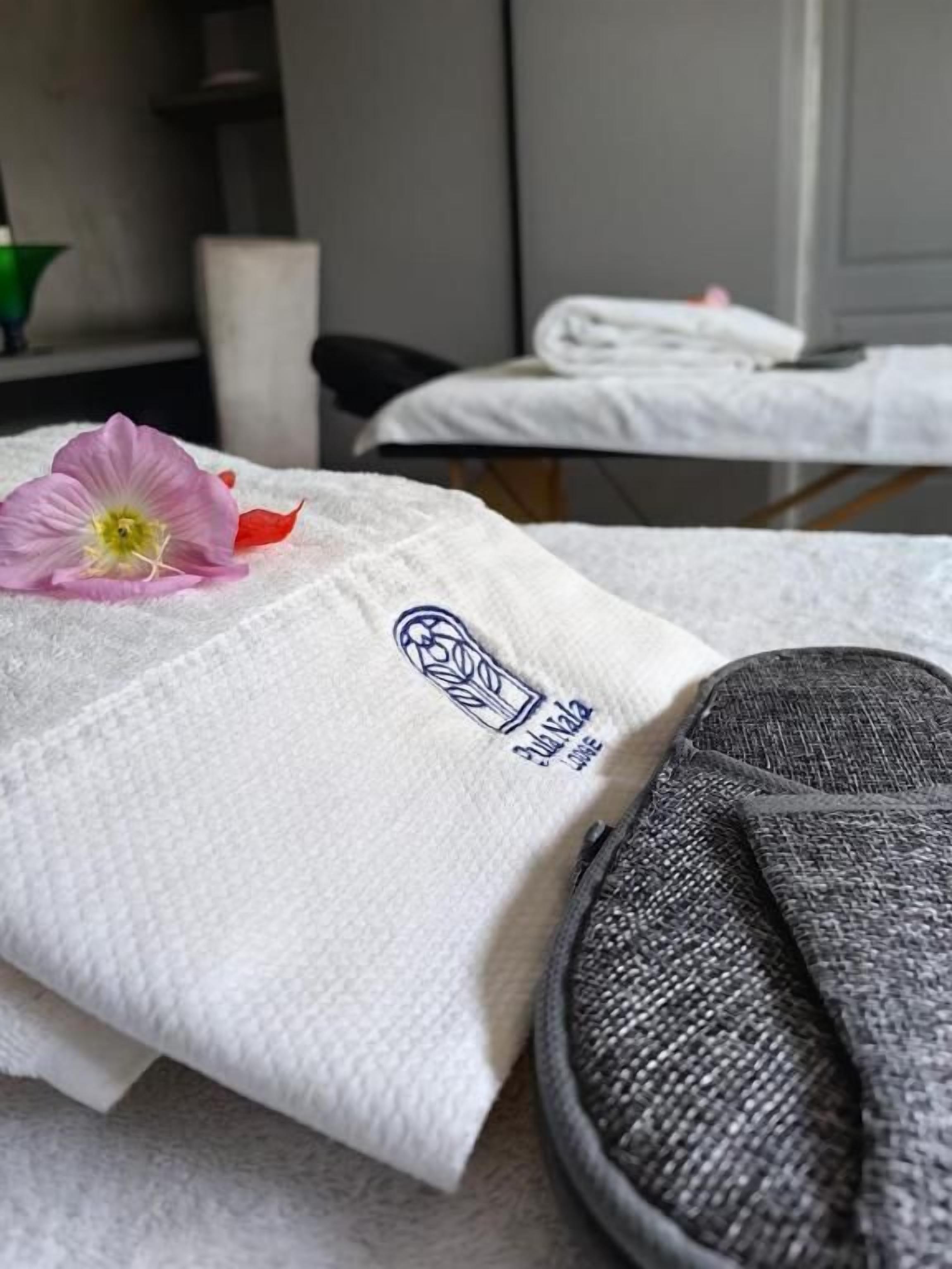 Eine Massageliege mit Handtuch und Blume.