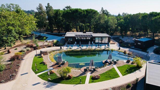A modern hotel with a central pool, outdoor seating, and a garden area. - Refúgio da Quinta Nere Maitia (Santarem)