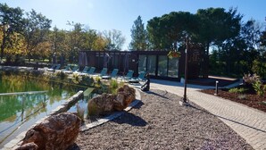 A pool area with lounge chairs and a modern building with glass walls. - Refúgio da Quinta Nere Maitia (Santarem)