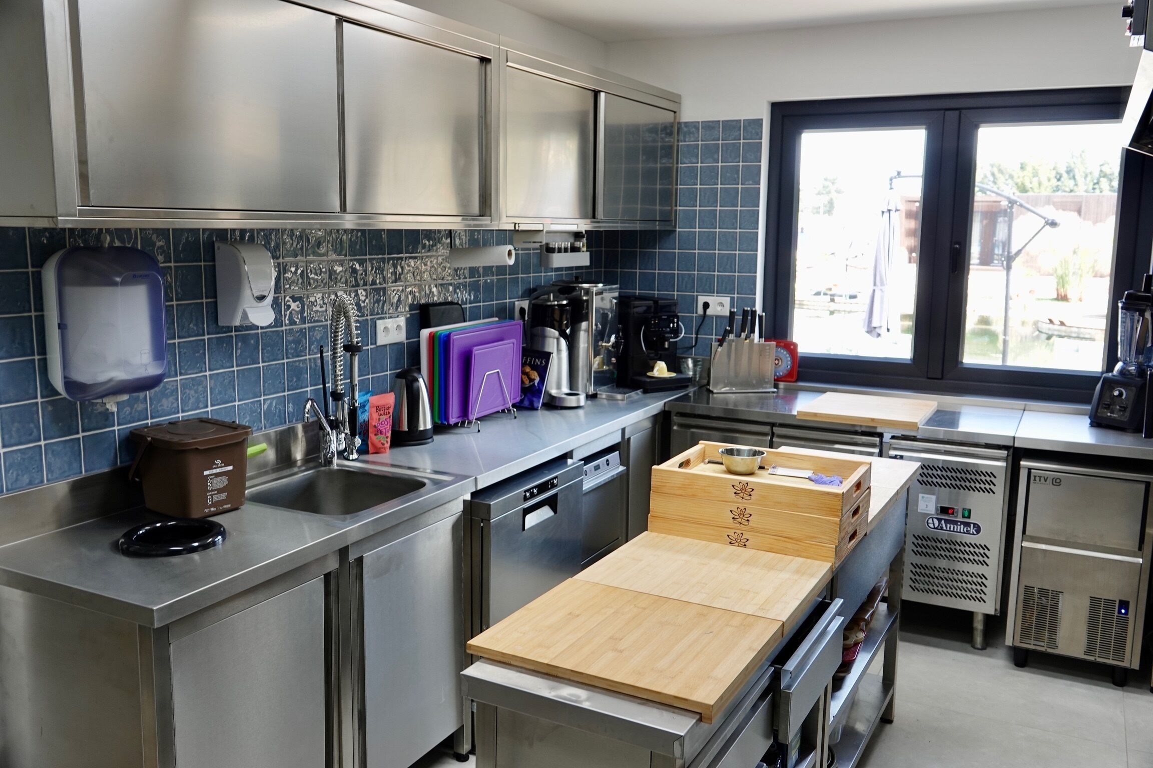 Una cocina moderna con electrodomésticos de acero inoxidable, lavavajillas y tabla de cortar de madera.