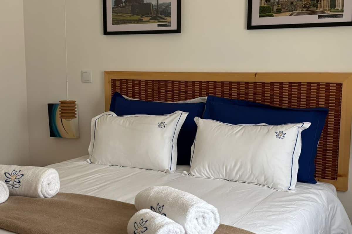A hotel room with two beds, a wooden headboard, white bedding, and two framed pictures on the wall.