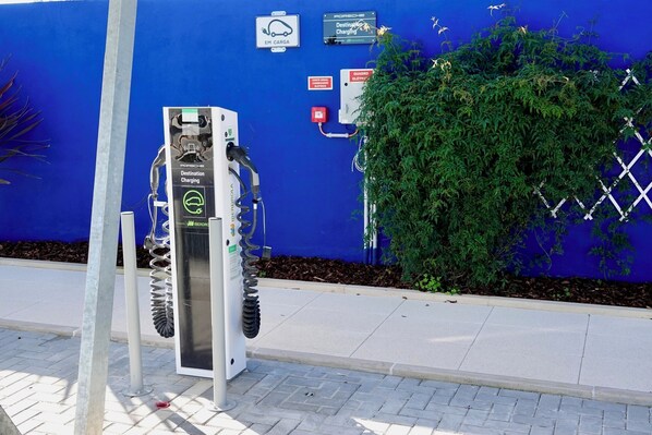 A charging station for electric vehicles, with a blue wall and greenery in the background. - Refúgio da Quinta Nere Maitia (Santarem)