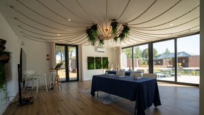 A spacious room with a large table, wooden flooring, and a ceiling with hanging plants. - Refúgio da Quinta Nere Maitia (Santarem)