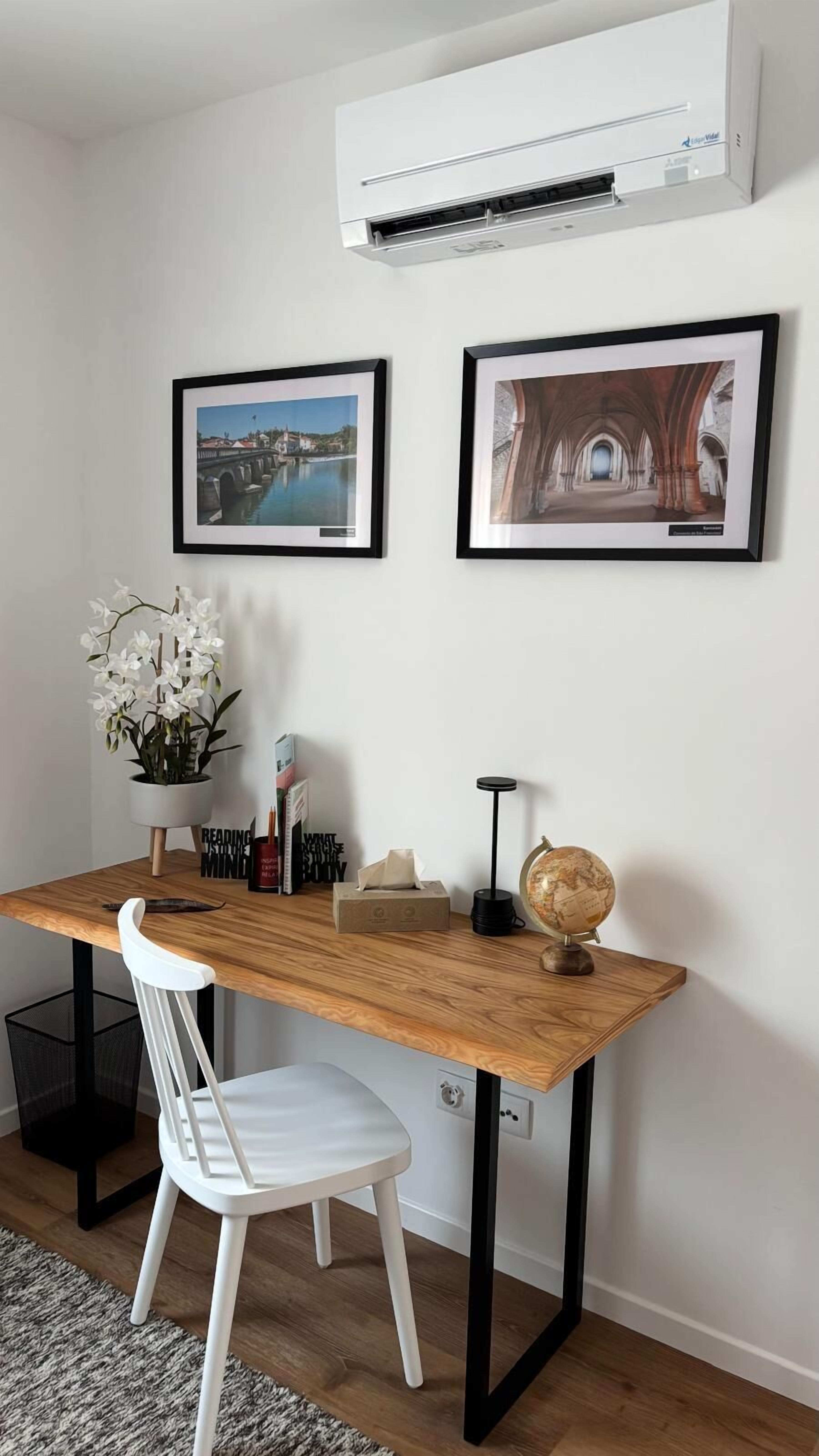 A modern office space with a wooden desk, white chair, and two framed pictures on the wall.