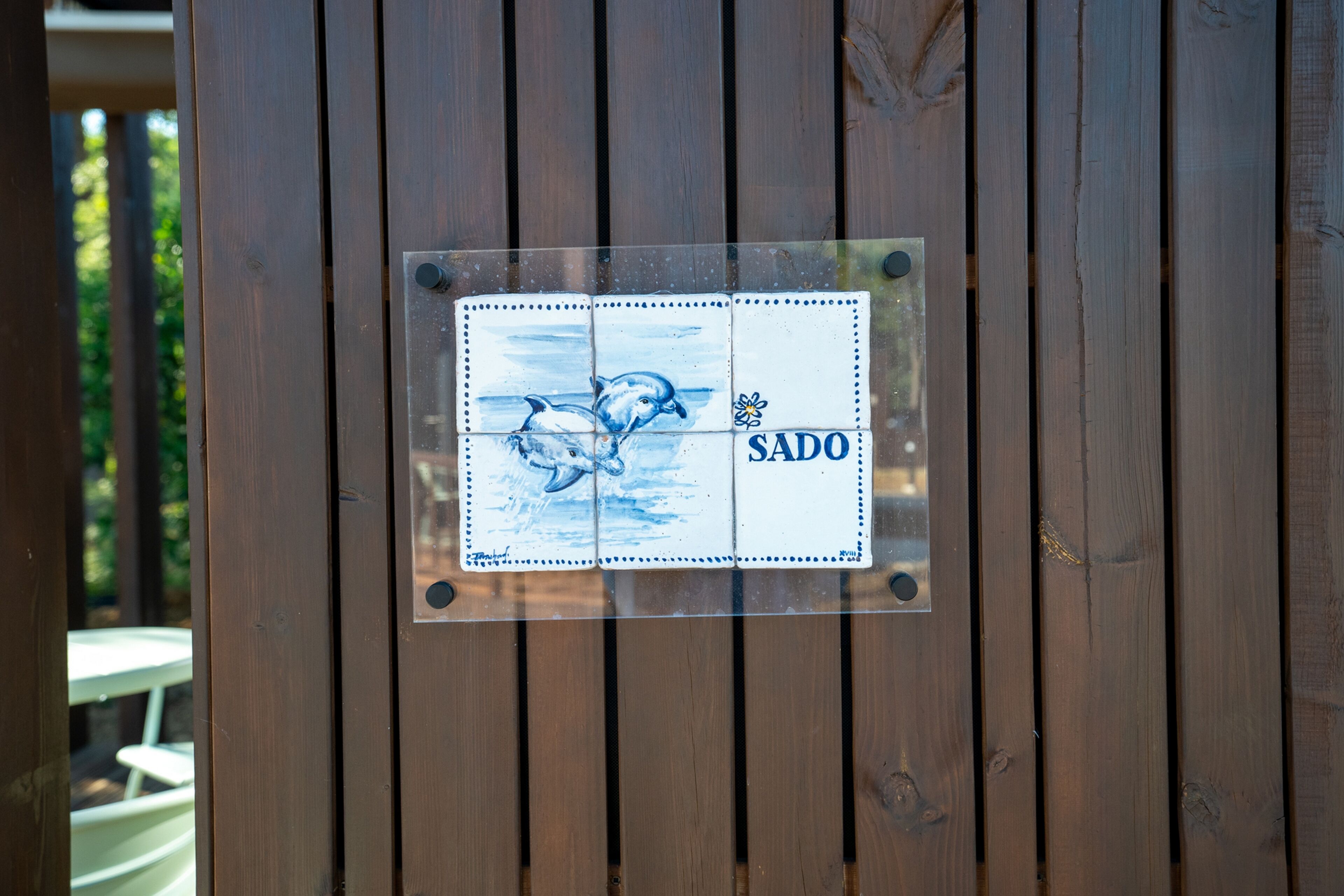Una puerta de madera con un letrero que muestra delfines y la palabra "SADO".
