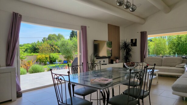 A modern dining area with a glass table, metal chairs, and a sofa.