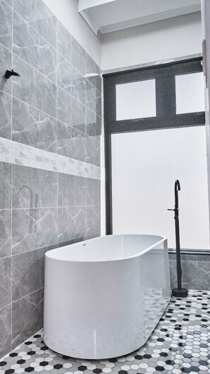 Une salle de bain moderne avec une baignoire sur pieds, des murs carrelés et un sol à motifs.