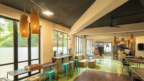 Um espaço de escritório moderno com uma mesa comprida, vários bancos e luminárias pendentes.