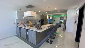 Una cocina moderna con una isla central, electrodomésticos de acero inoxidable e iluminación colgante.