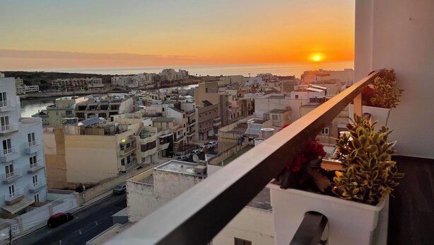 Un balcón con vista a un paisaje urbano al atardecer.