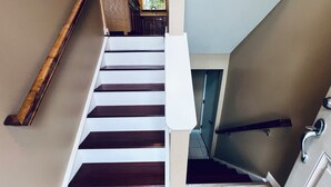 A staircase with dark wooden steps and white risers, leading to a landing with a door. - NEW Spacious Home Minutes From Oneida Lake & Fall Festivities!  (Brewerton)