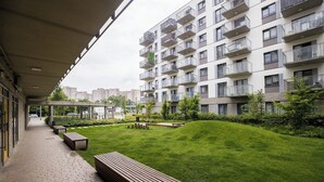 A modern apartment building with balconies, a covered walkway, and a well-maintained lawn. - ShortStayPoland Wileńska B165 (Warsaw)