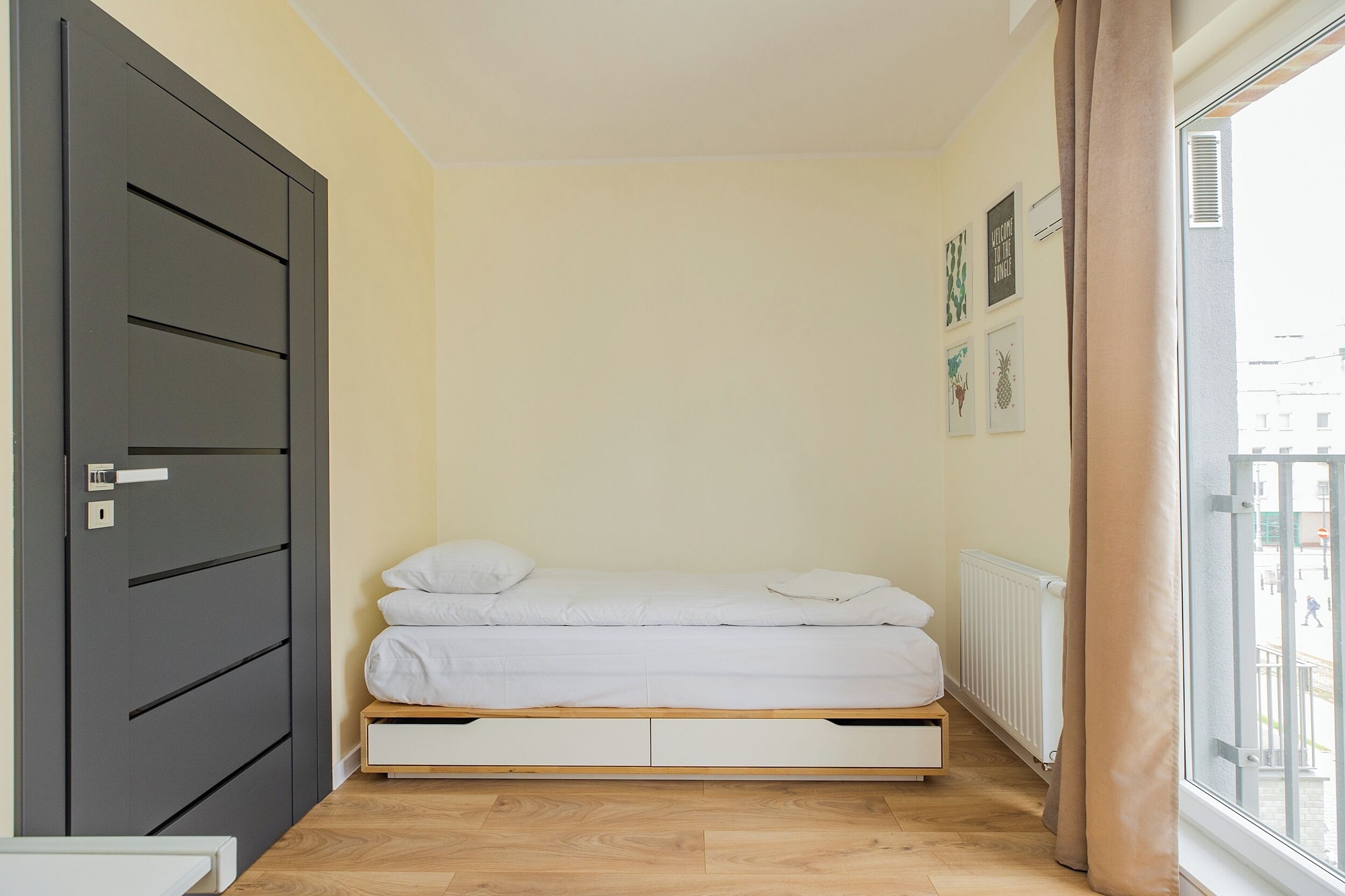 Un dormitorio pequeño y ordenado con cama, armario y ventana con cortinas.