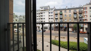 A view from a balcony overlooking a street with multi-story buildings, a clear sky, and a few parked cars. - ShortStayPoland Wileńska B165 (Warsaw)