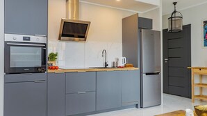 A modern kitchen with grey cabinets, a built-in oven, a stainless steel refrigerator, and a microwave. - ShortStayPoland Wileńska B165 (Warsaw)
