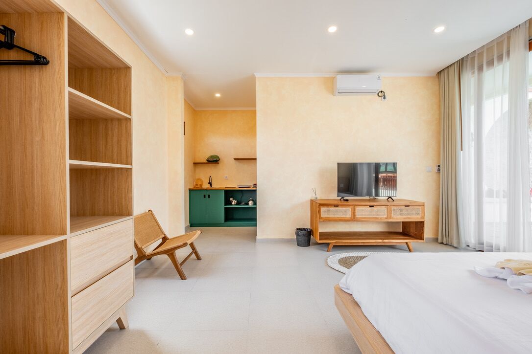Une chambre d’hôtel moderne avec un lit, des meubles en bois, une télévision et une armoire verte.