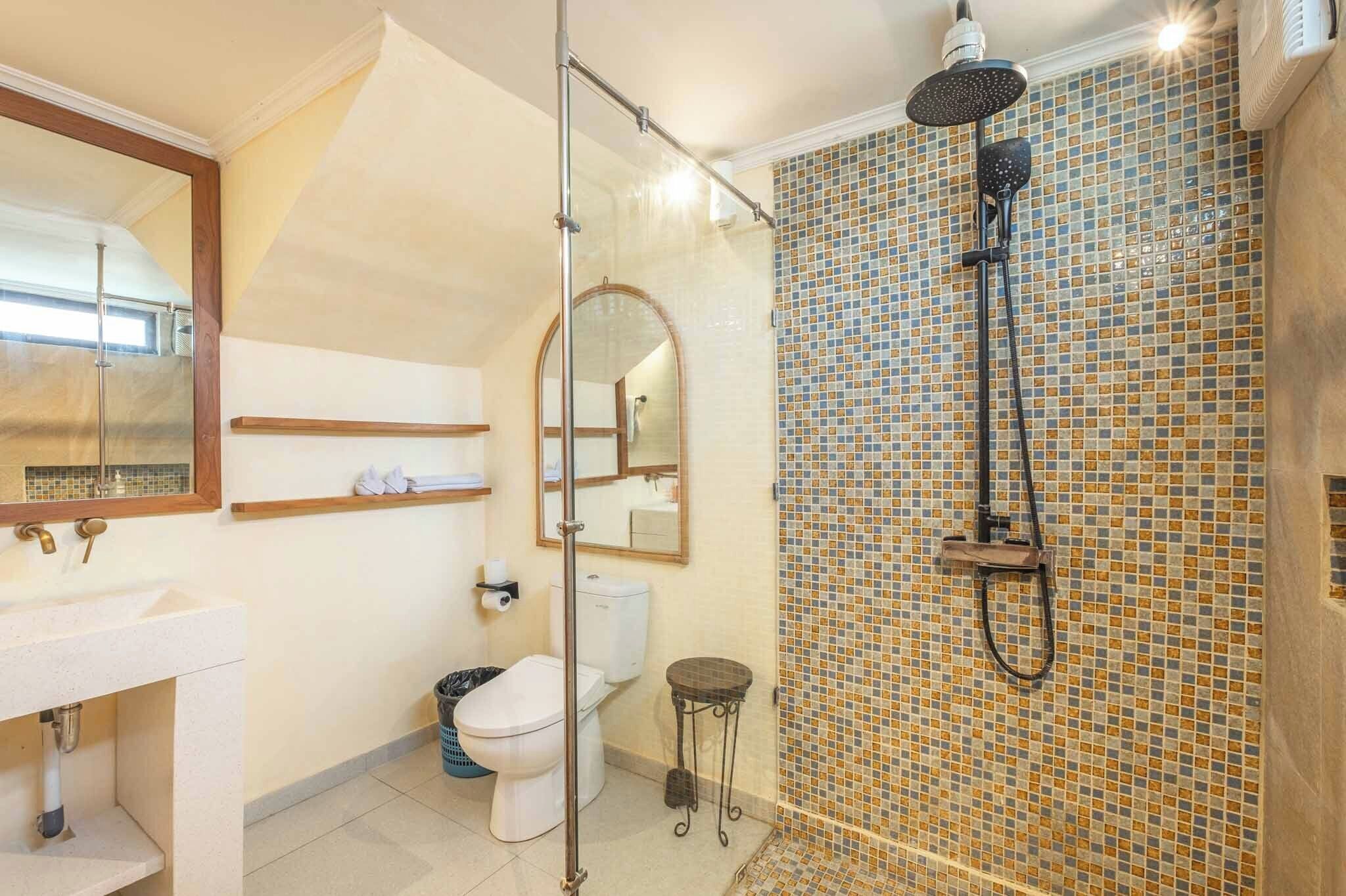 A bathroom with a shower, toilet, sink, and a mirror.