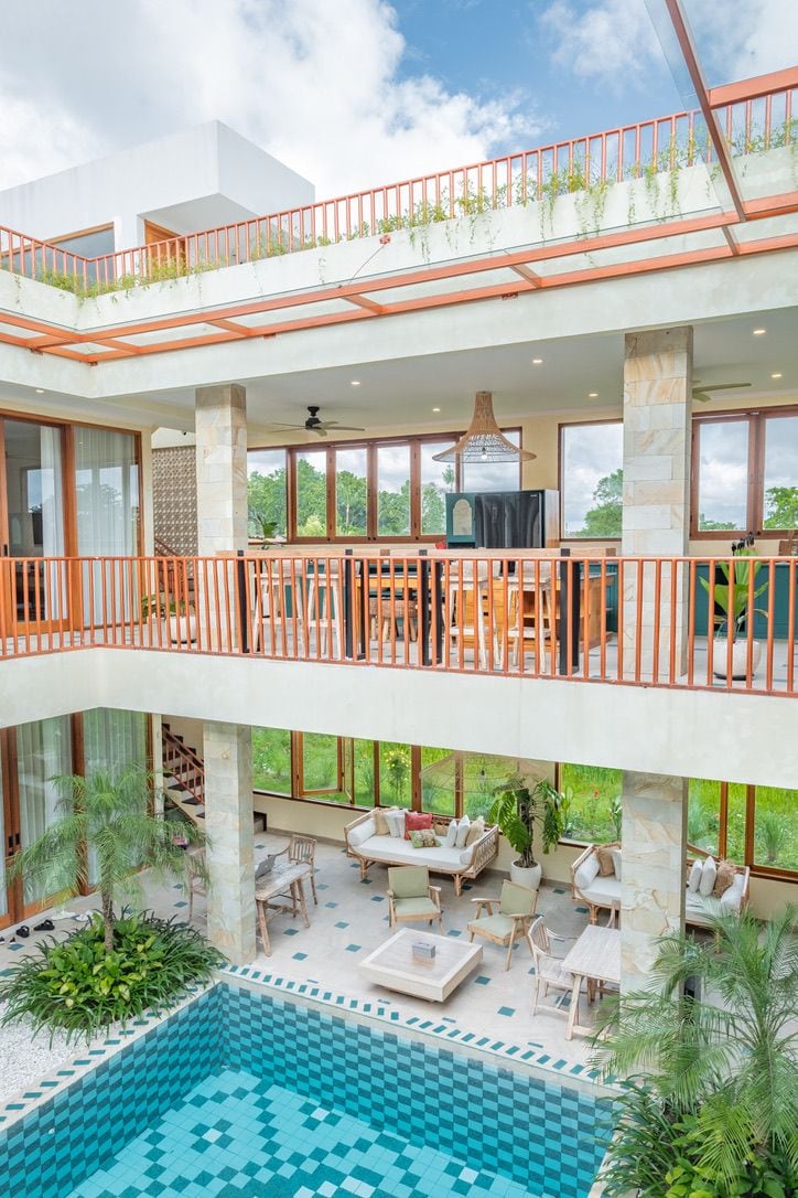 A multi-level outdoor living space with a pool, seating areas, and a balcony with plants.