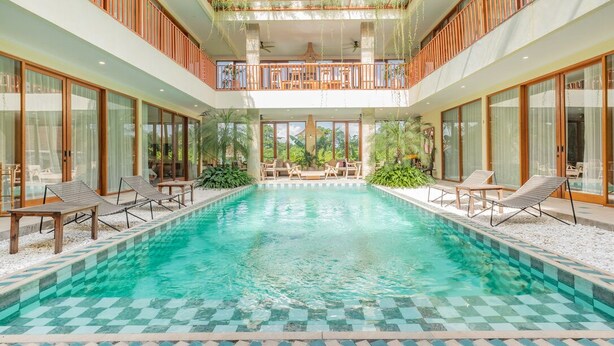 Un'ampia piscina coperta con lettini e un balcone con vista sulla piscina.