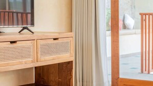 Un mobile TV in legno con TV a schermo piatto, un cesto intrecciato e una panca in legno.