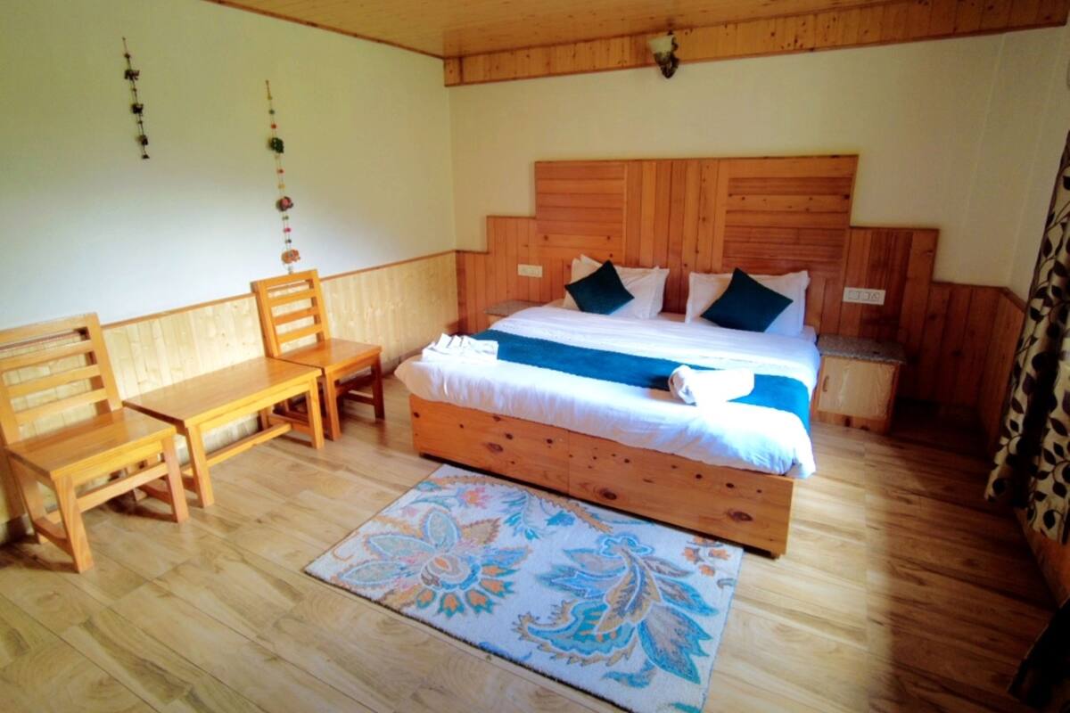 Un dormitorio con estructura de madera, una cama, un escritorio y una silla.