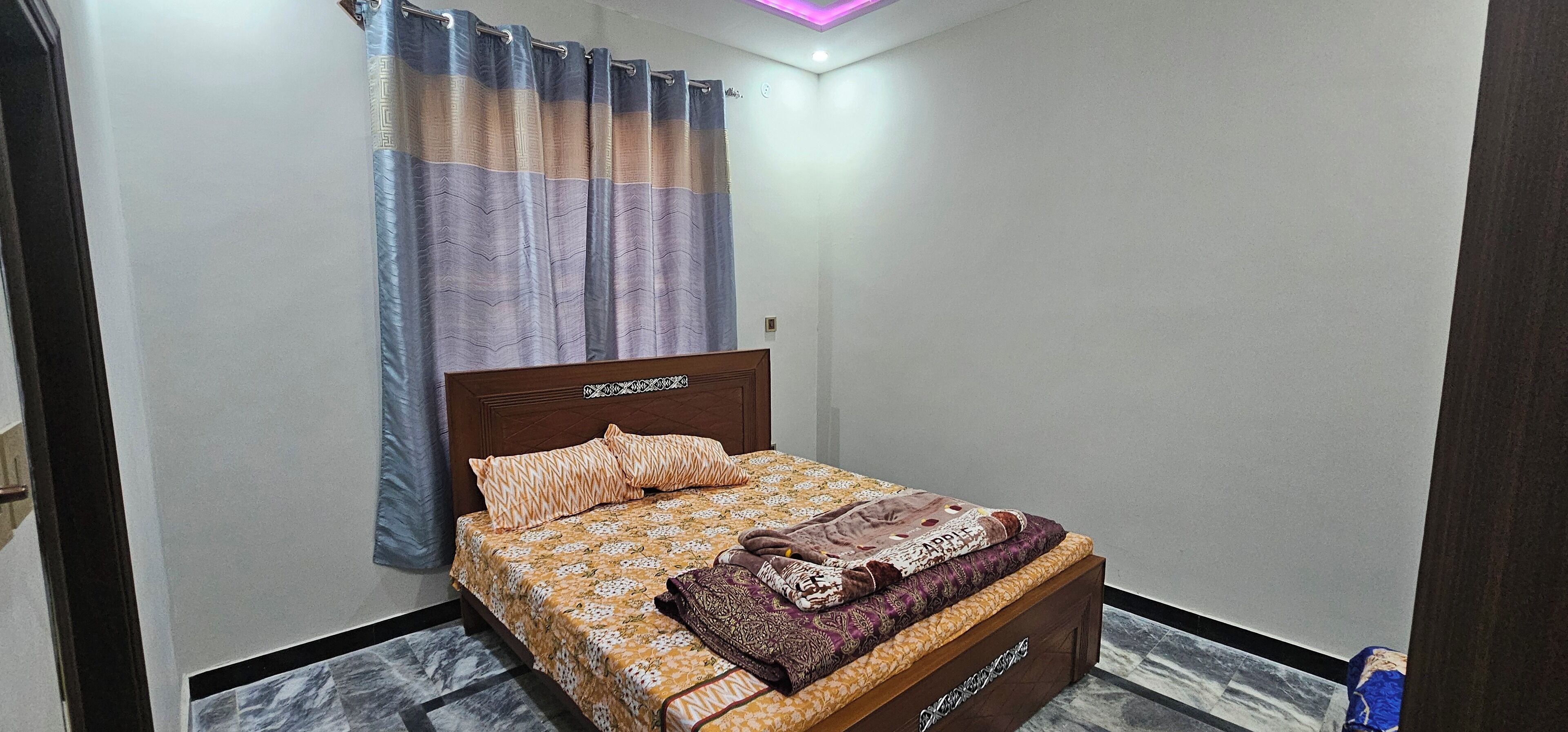 A bedroom with a bed, curtains, and a ceiling light.