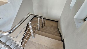 A staircase with a metal handrail and beige steps. - Mirpur 3-bed House Sleeps 6 (Mirpur)