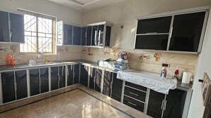 A kitchen with black cabinets, a window, and a tiled backsplash. - Mirpur 3-bed House Sleeps 6 (Mirpur)